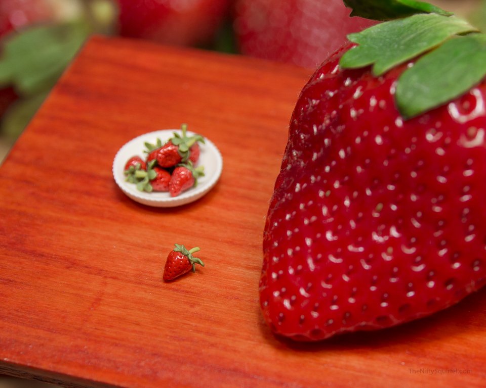 A realistic miniature strawberry, next to a real strawberry
